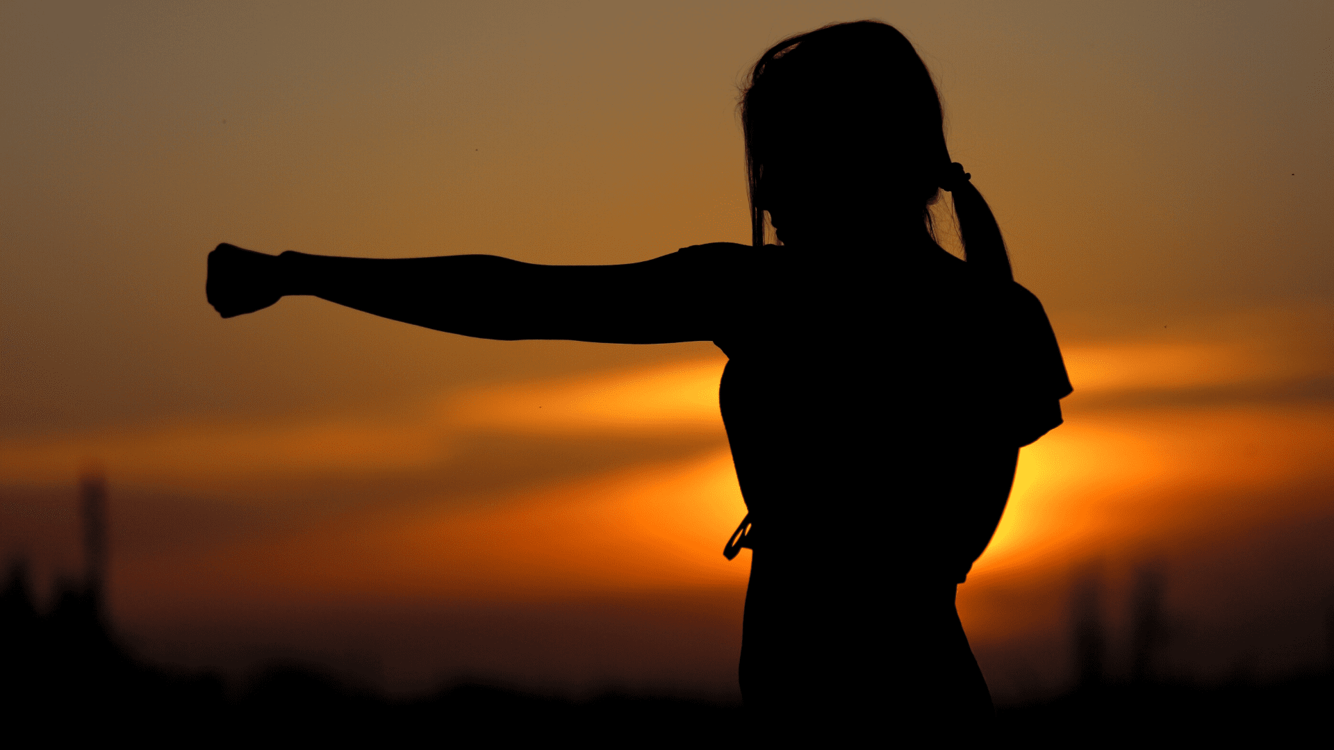 Femme qui pratique le karaté en plein air avec un coucher de soleil